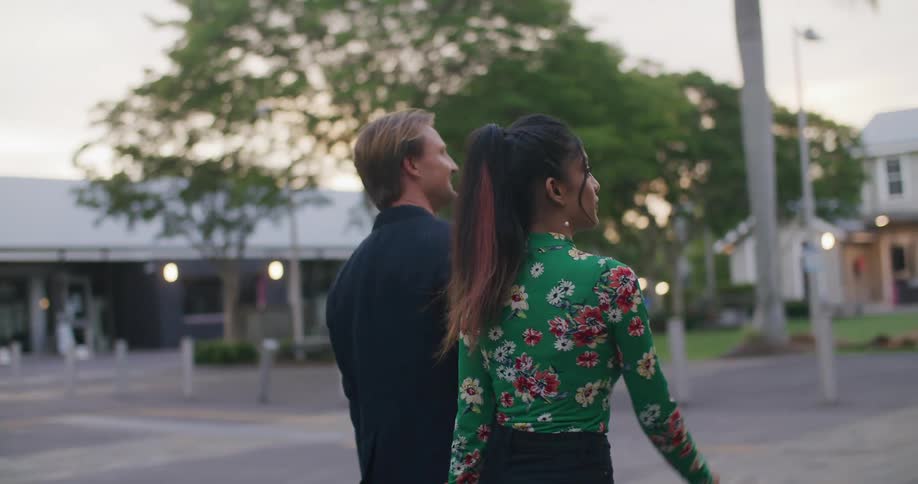 A woman and a man walking and talking on the street at sunset