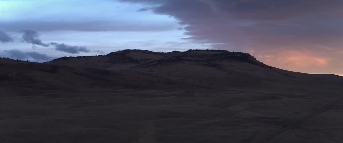 Mountainous hills under a colorful cloudy sky