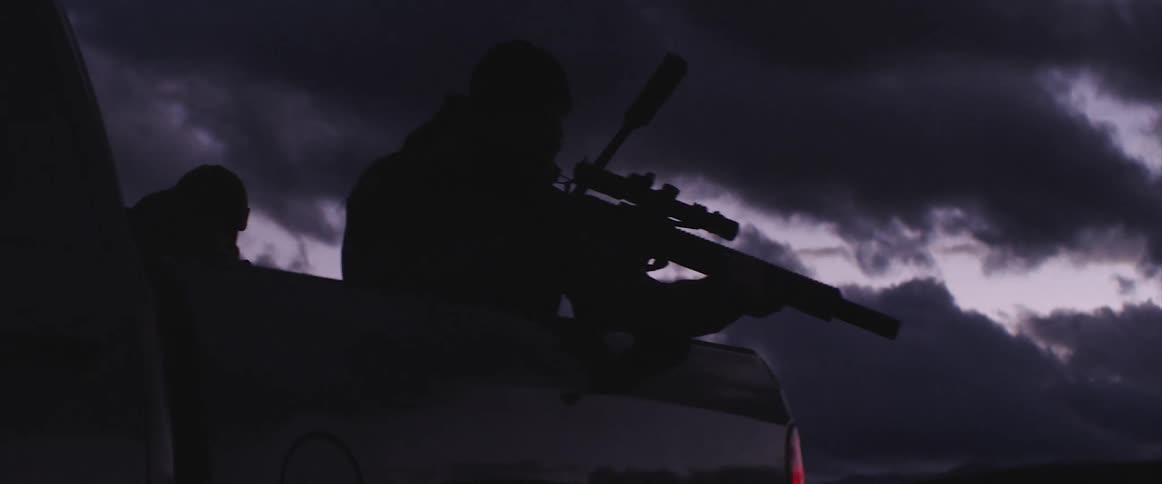 Two soldiers aiming assault rifles from the back of a pickup truck