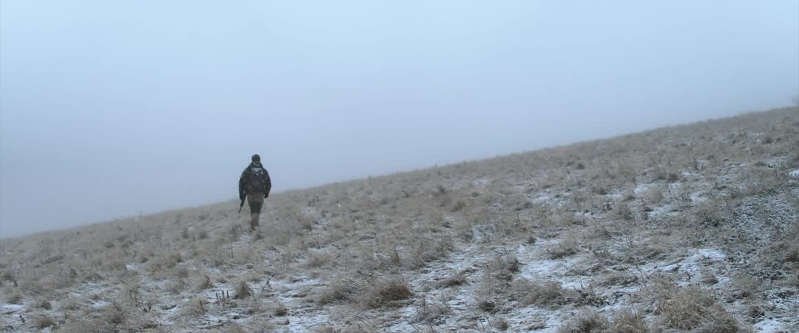 A man is hiking through a grassland area