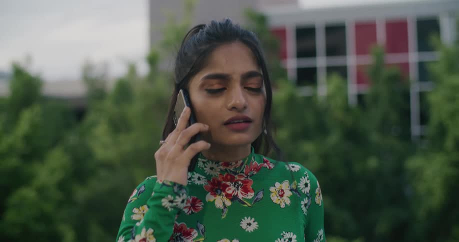 A woman is standing outdoors and talking on a cellphone