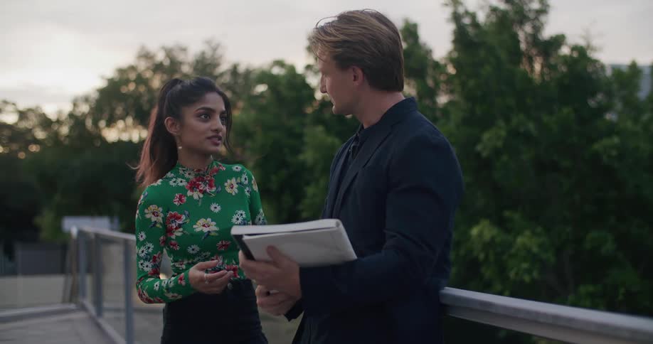 Woman and man talking while standing on a bridge at sunset
