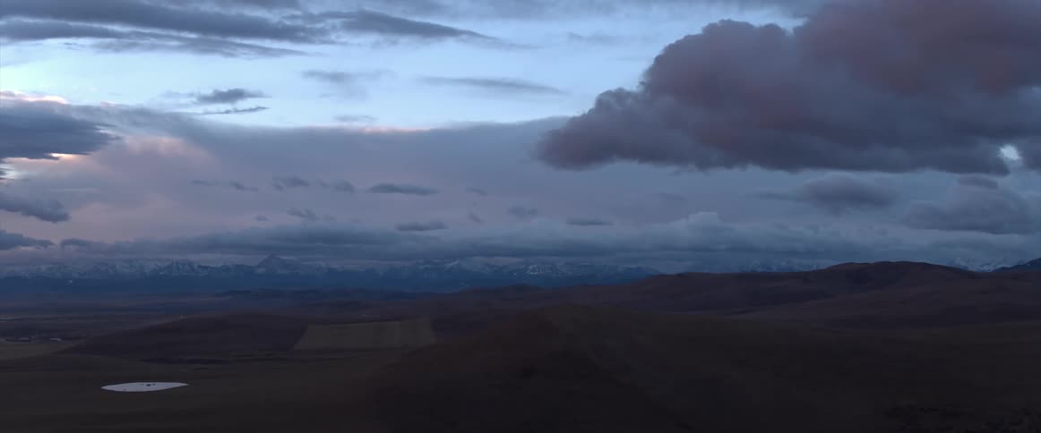A view of clouds moving over a landscape at sunset