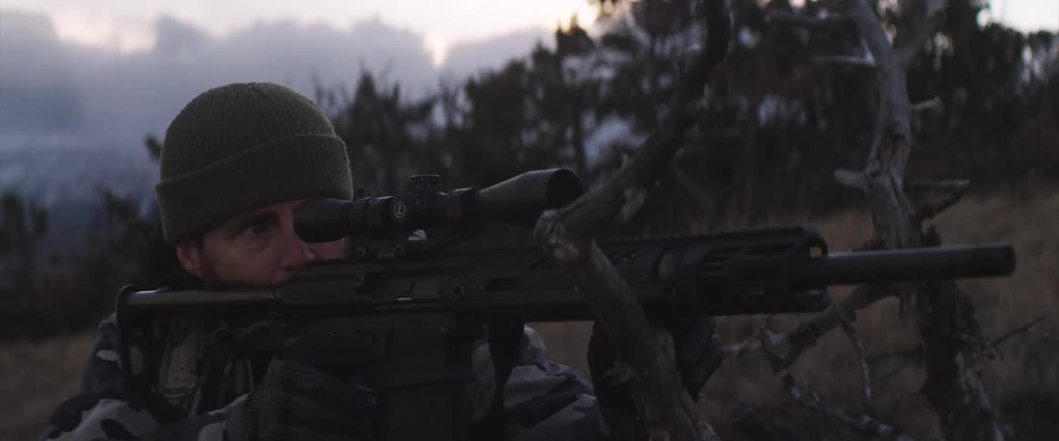 Man looking through rifle scope