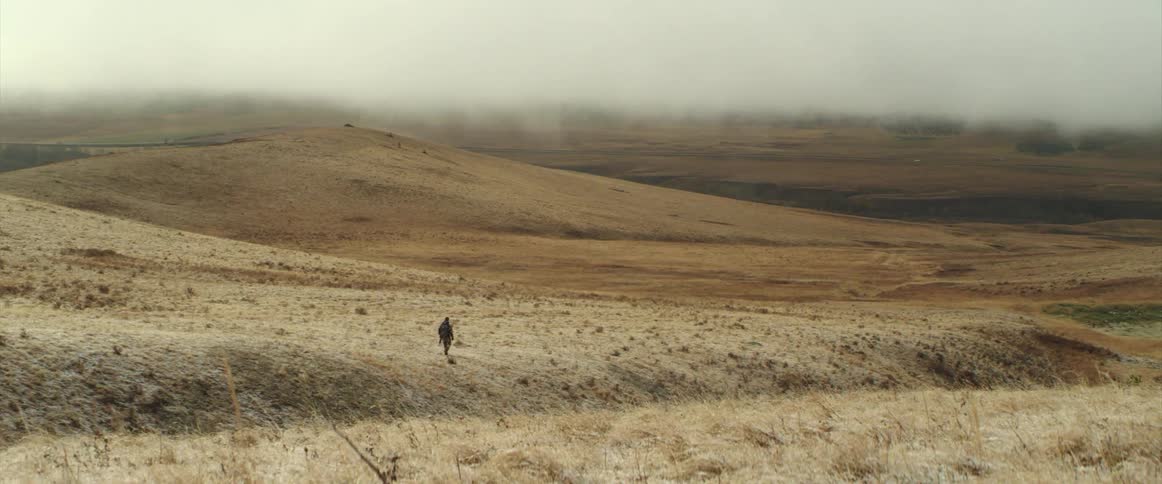 Person walking across dry land with hills