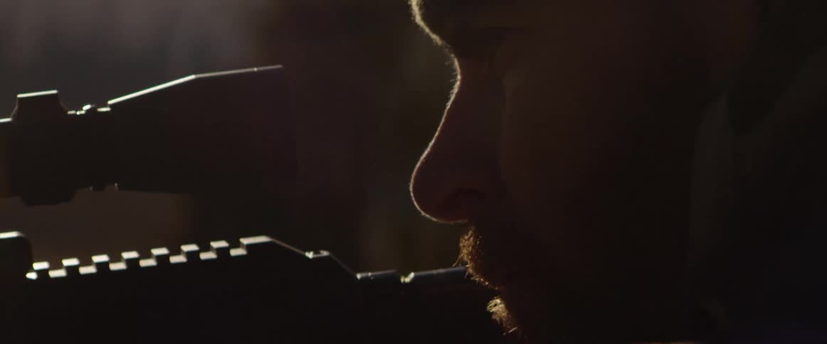 A man outside aims his gun