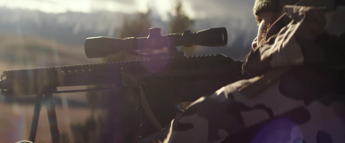 A man outside aims his gun