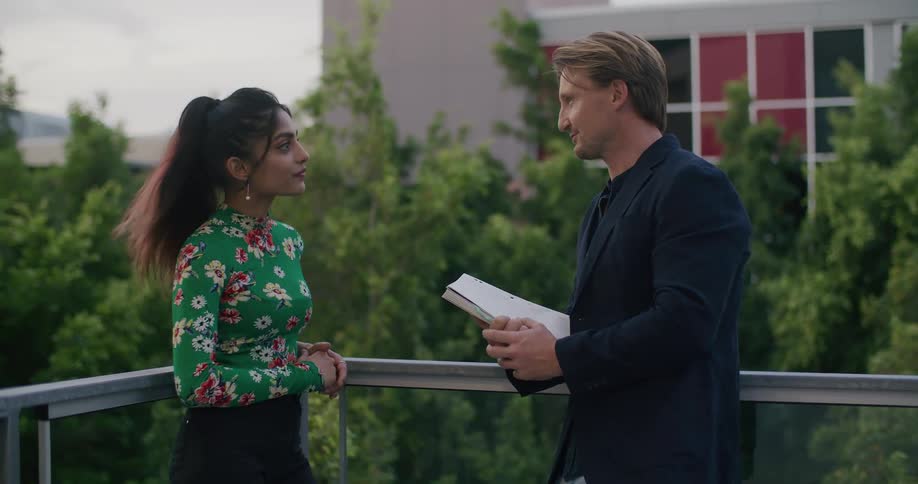 A woman and a man talking on the balcony of a building