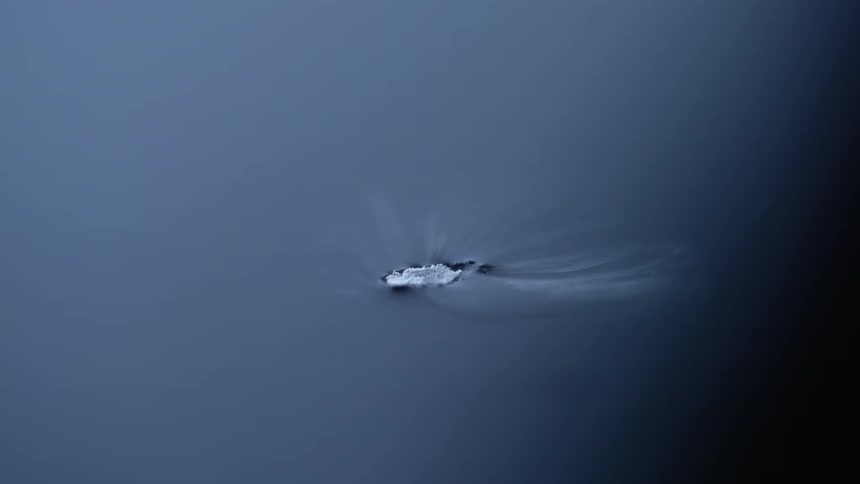 White smoke floating and swirling around dry ice over a black reflecting surface
