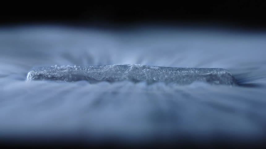 White smoke floating and swirling around dry ice over a black reflecting surface