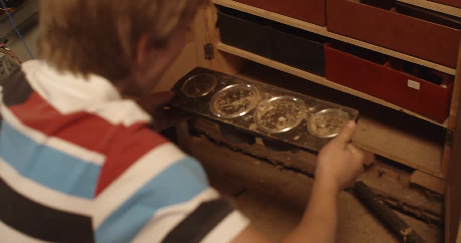 A boy pulls a dial component from the shelf in the cabinet