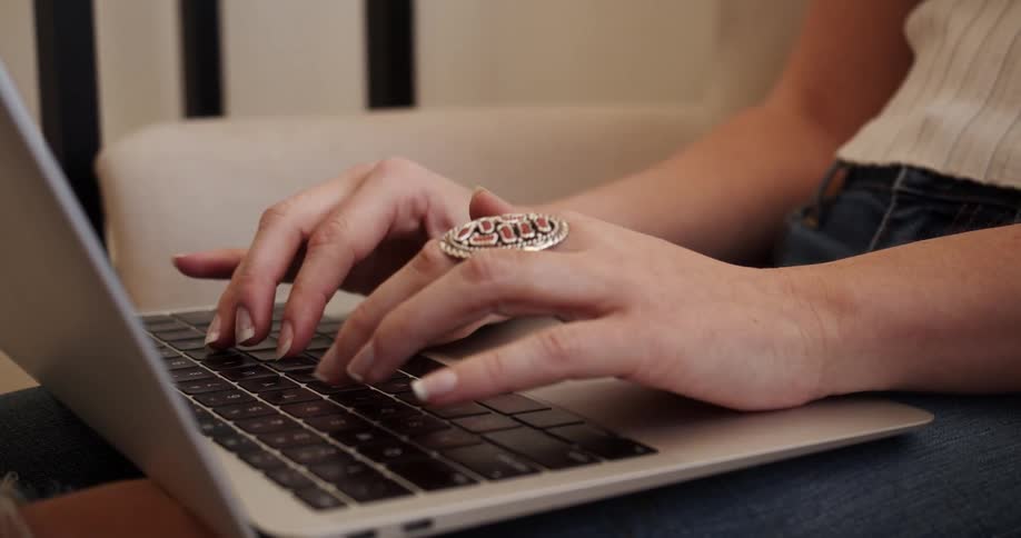 Woman wearing large ring types on laptop set in her lap