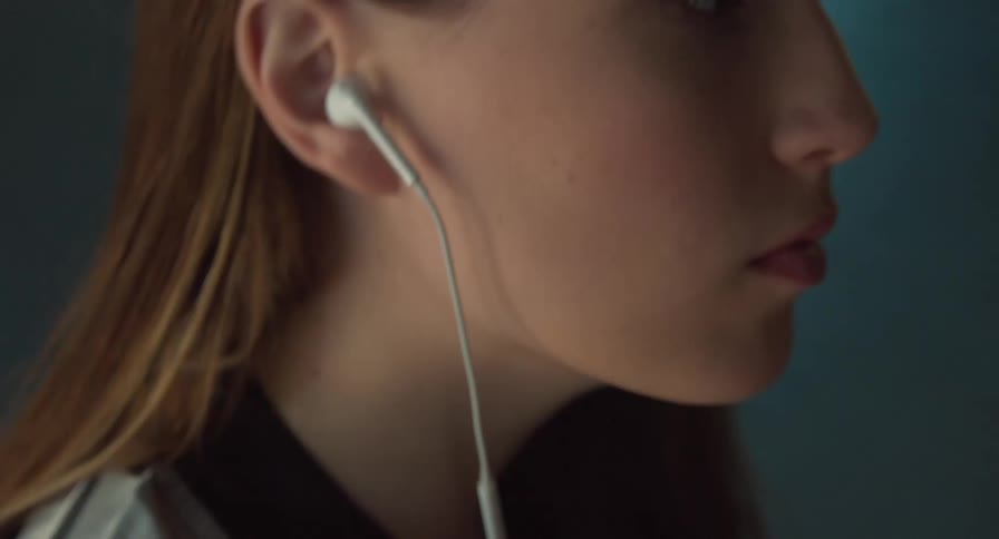 A teenage girl removes wired earbuds from her ears