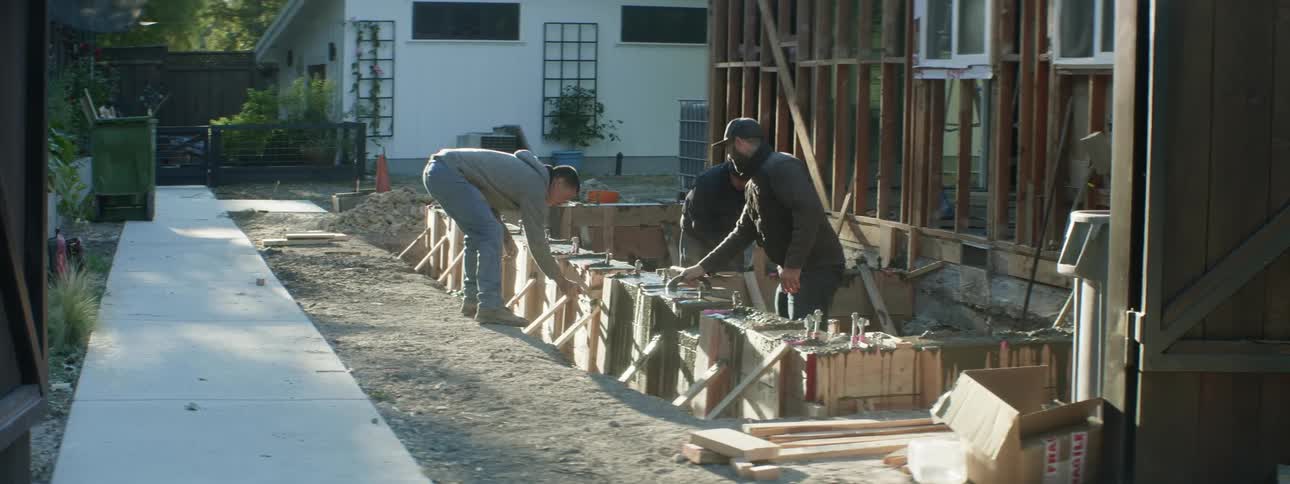 A group of workers working on the construction of a house annex at sunset