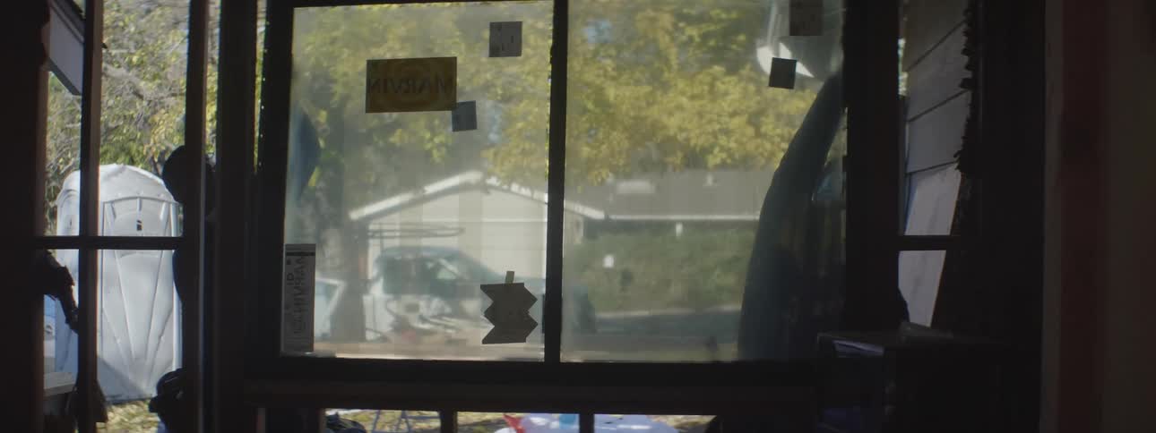 Two construction workers installing a window in a house