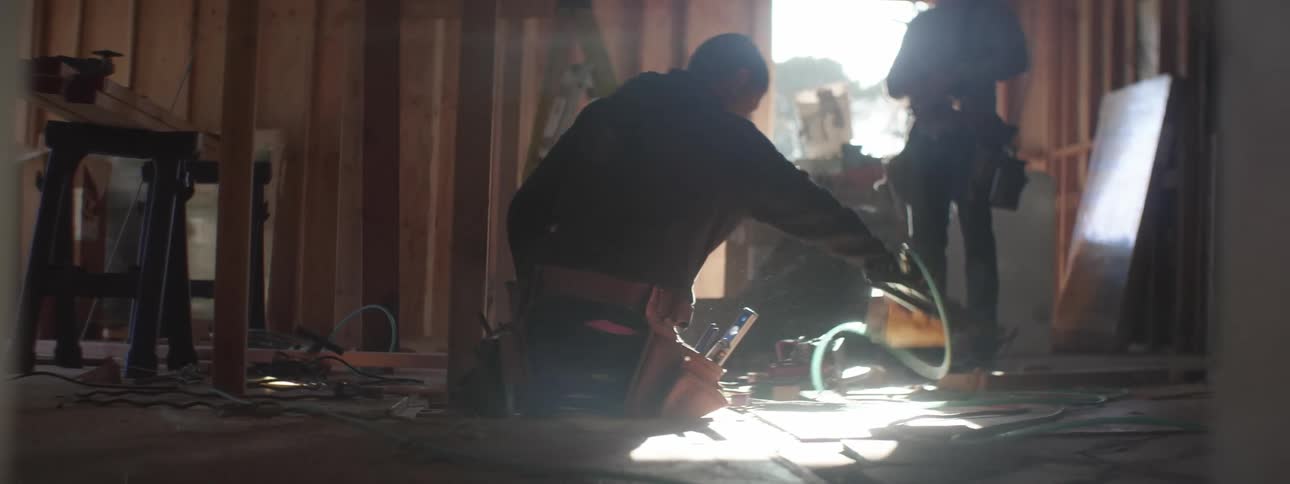 Men work on construction site in light coming in through unfinished doorway