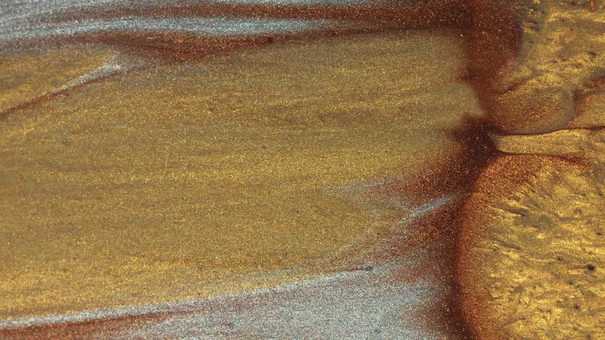 Blobs of gold and copper paint move onto a flat surface of paint