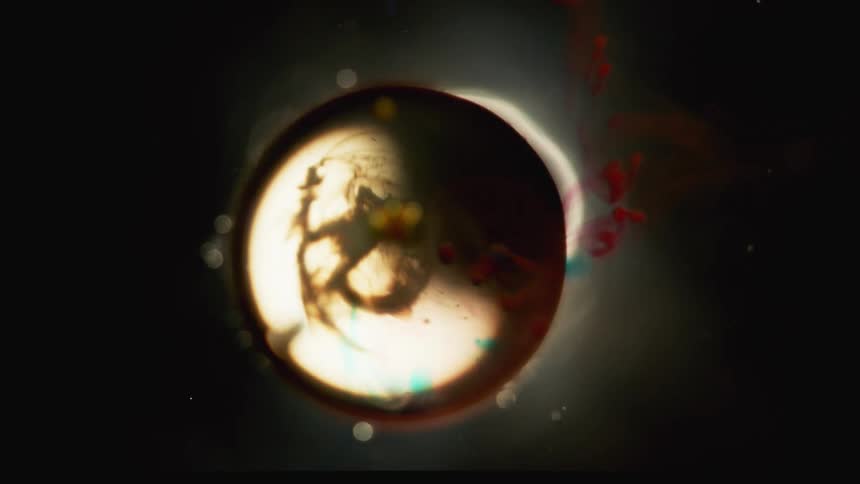 Glass ball submerged on liquid surrounded by red and blue ink