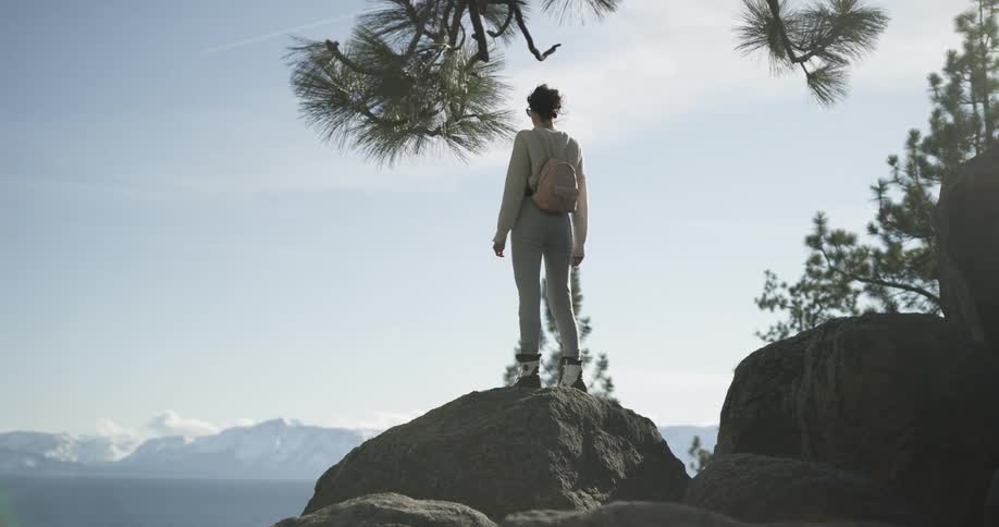 A woman walking on boulders while hiking alone in mountains