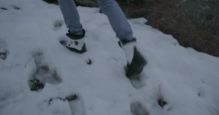 A woman is hiking up the snow filled hill