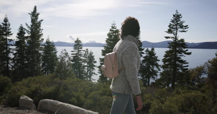 A woman hiking alone near a forest lake on a summer day