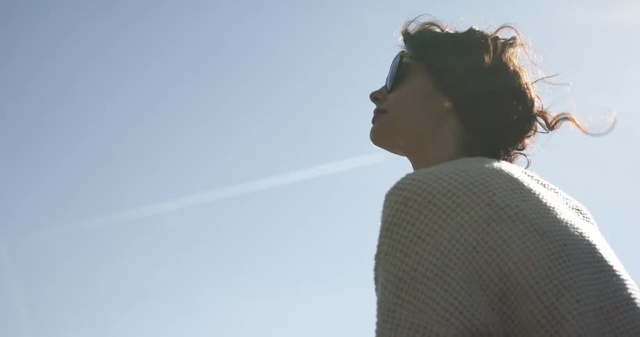 Woman sits looking up at the sky on a sunny day