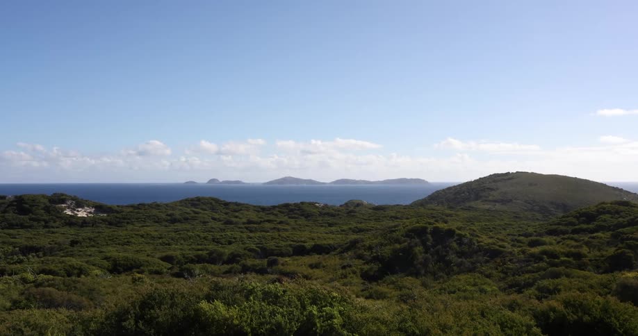 Distant islands on the horizon seen from the lush green vegetation on the mountains near the ocean