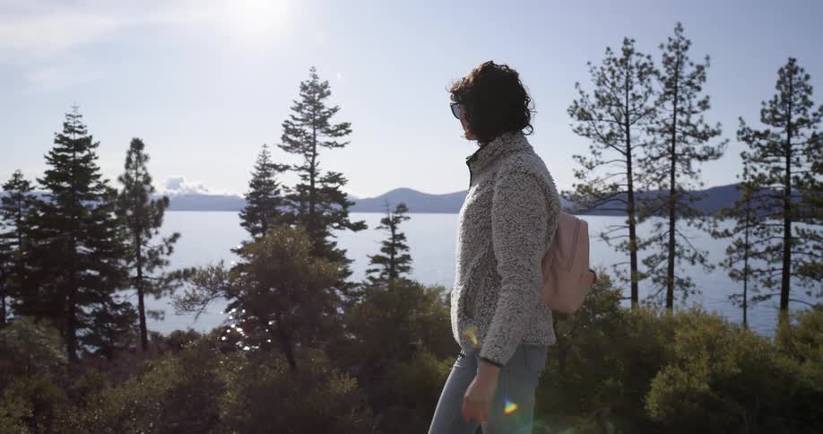 A woman hiking alone near a forest lake on a sunny day