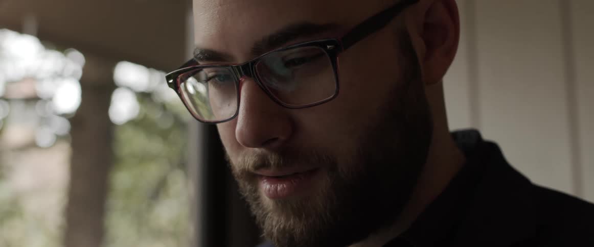 A man is talking and wearing glasses in a house