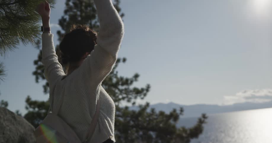 A woman cheers by the lake