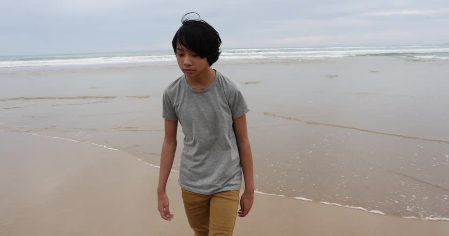 A boy is walking on the beach