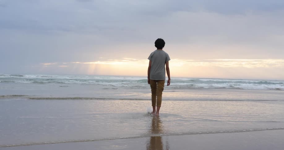 A lone person walking barefoot on a sandy beach