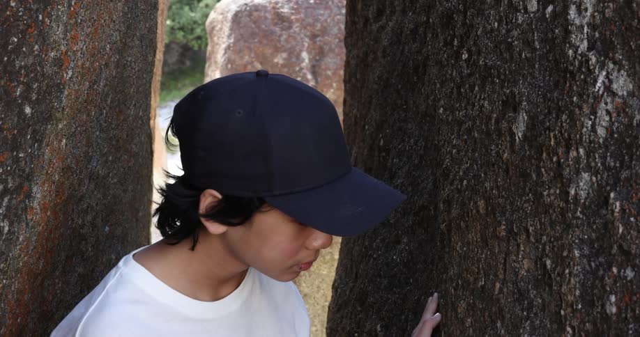 A child looking at a rock wall outdoors