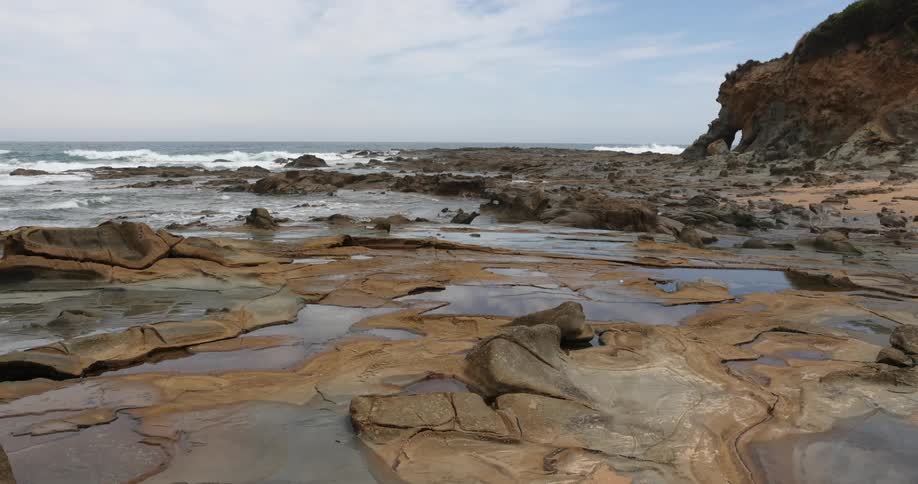 Ocean waves splash and break on a rocky shore during low tide