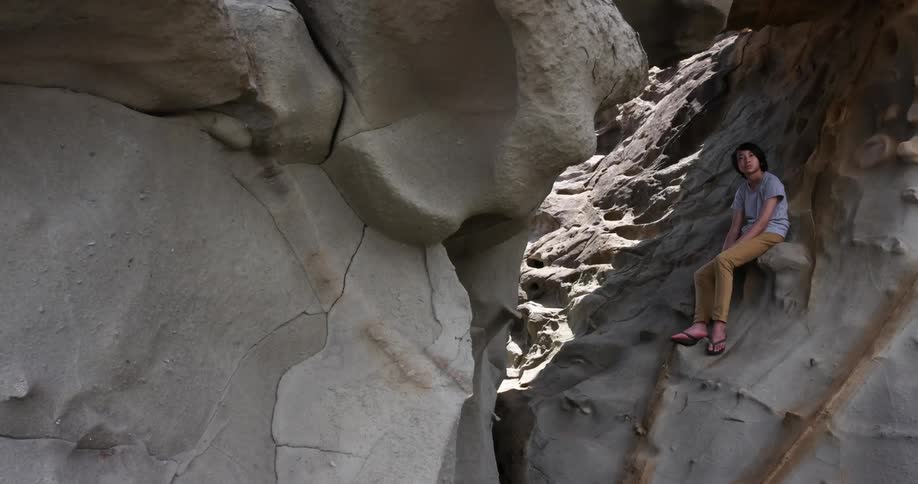 A man with a t shirt sitting on a rocky cliff