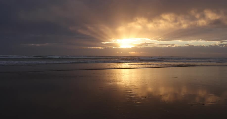 A beach with sand with the ocean the sky and clouds in the background