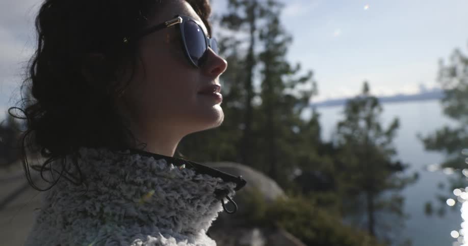 A woman is standing outdoors and wearing sunglasses