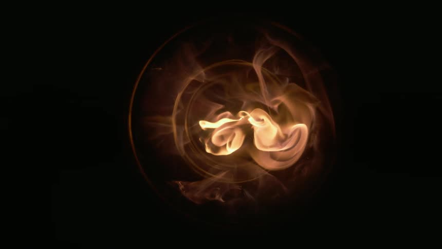 A gold flame bursts and glows through a round opening before slowly fading