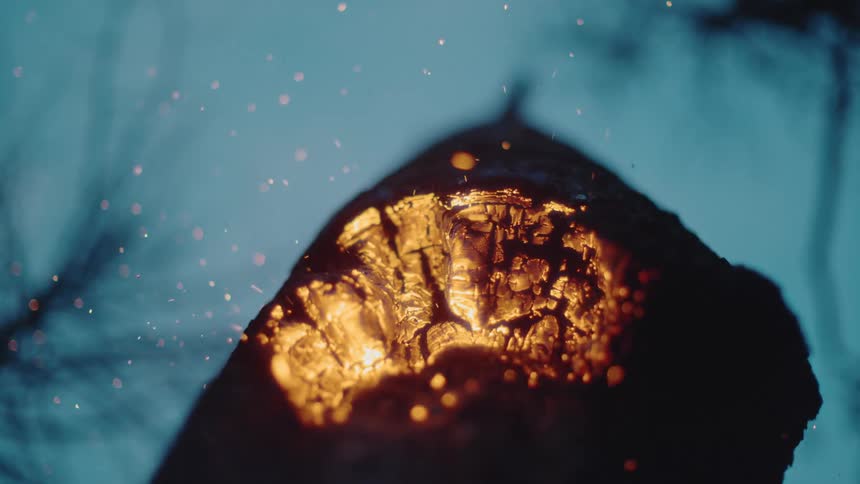 Embers rise from burning charred wood