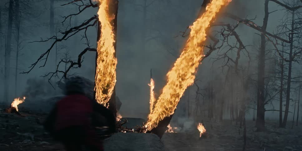 A person jumps his mountain bike through burning trees