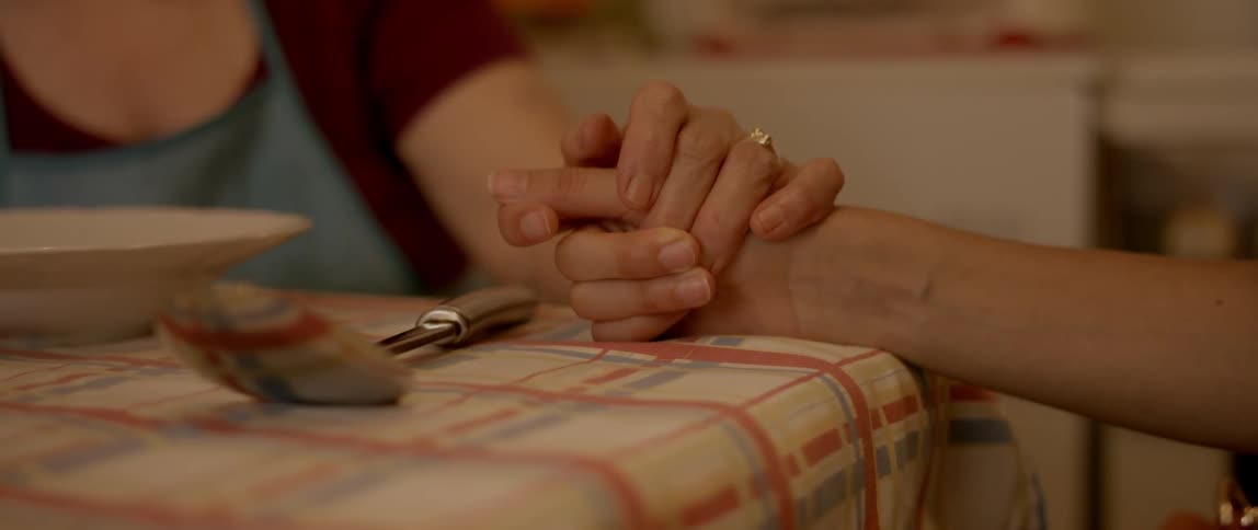 Two people are holding hands on a table