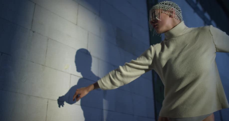 A woman in a room dancing next to a wall