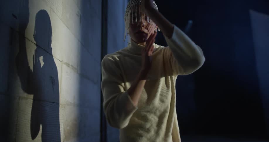 A woman in a room dancing by a wall