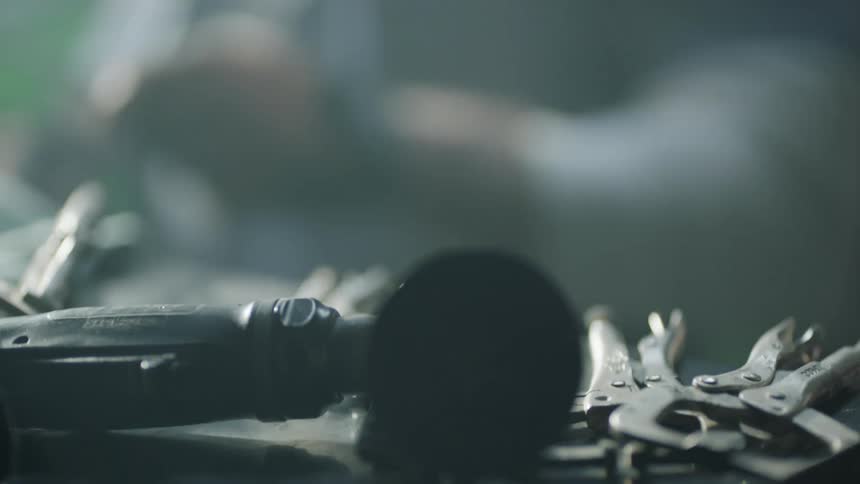 An employee grabbing a wrench off a table
