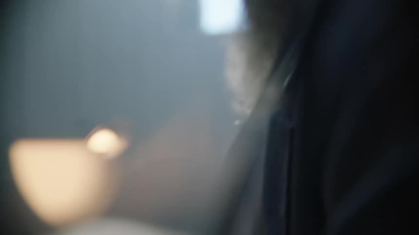 Bearded man checking a tool inside a dimly lit workshop
