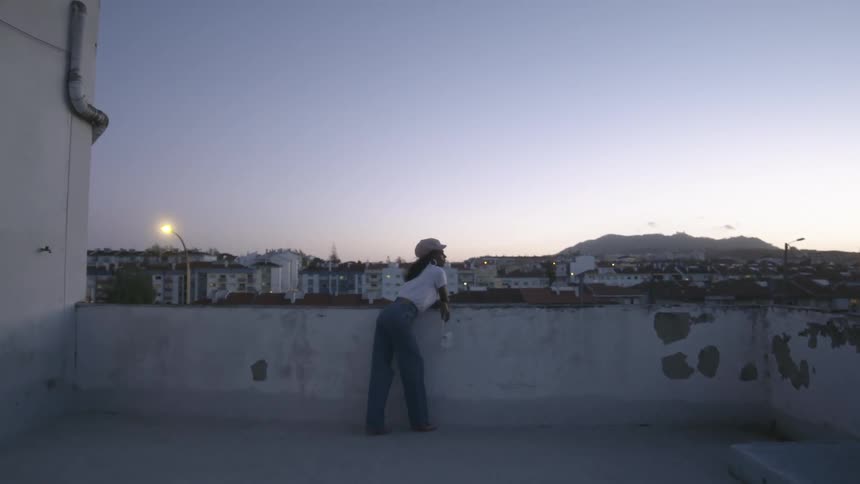 A woman is watching the city from the rooftop