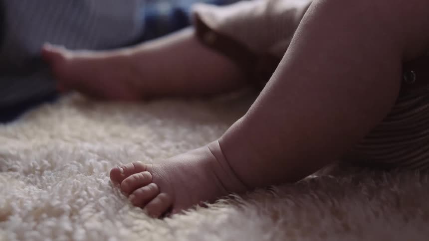 A baby is moving his feet around on the carpet