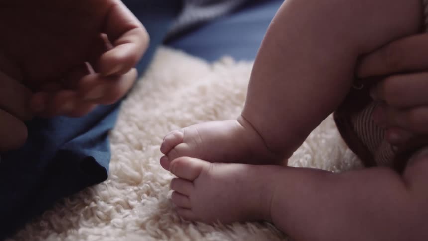 Mans hand touches babys small feet