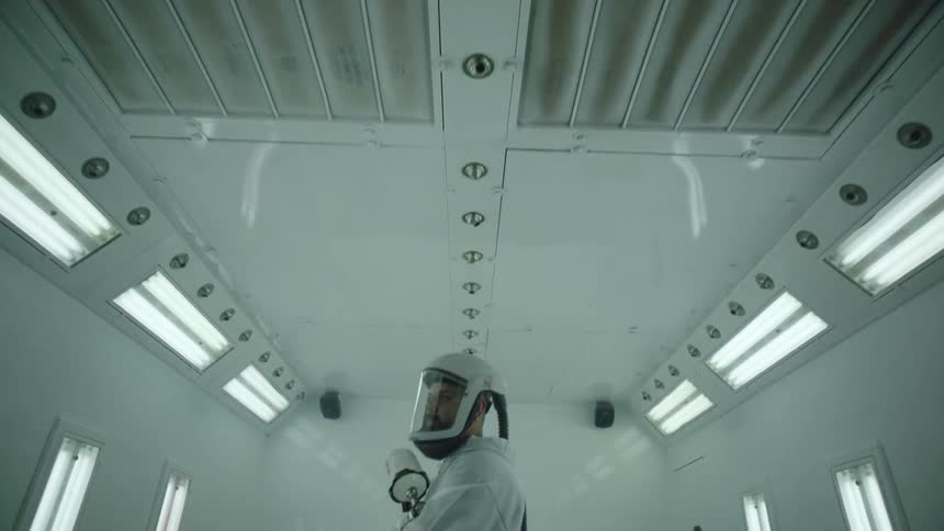A man in a hazmat suit is holding a spray nozzle