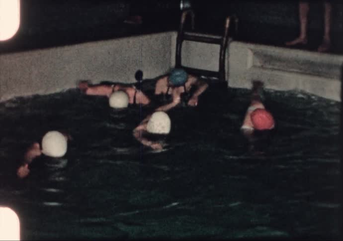 Women practice freestyle strokes during swimming lessons in the 1960's